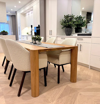 Angled view of the Amsterdam Dining Table in a dining room setting, highlighting its sleek edges, sturdy base, and contemporary design.