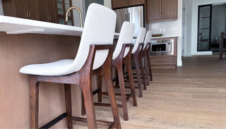 Side view of the Plymouth Counter Stool positioned by a kitchen island, showcasing its sleek frame, comfortable seat, and clean, modern design.